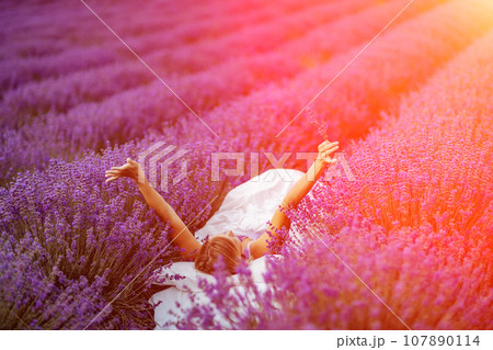Woman lavender field. A middle-aged woman lies in a lavender field and enjoys aromatherapy. Aromatherapy concept, lavender oil, photo session in lavender 107890114