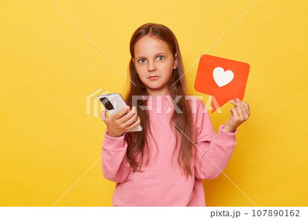 Engaging with social media content shocked brown-haired young girl in pink sweatshirt explores internet viewing various online materials expresses appreciation by clicking on heart icon. Engaging with social media content shocked brown-haired young girl in pink sweatshirt explores internet viewing various online materials expresses appreciation by clicking on heart icon. 107890162