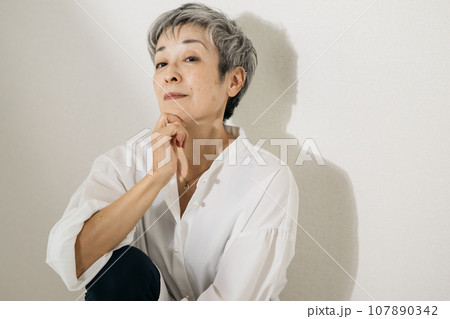 立膝で座る、白いシャツを着たグレイヘアの上品な日本人女性 107890342