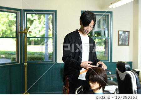 ヘアマネキンでカット練習をする男性美容師 ヘアマネキンでカット練習をする男性美容師 107890363
