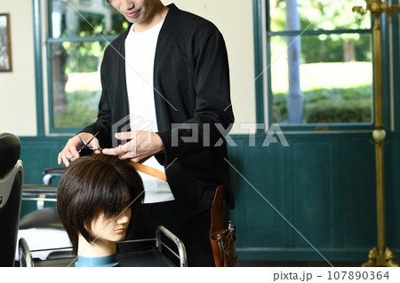 ヘアマネキンでカット練習をする男性美容師 ヘアマネキンでカット練習をする男性美容師 107890364