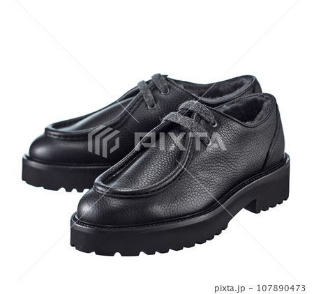 Stunning pair of men's derby boots made of thick black leather, with lacing, insulated with natural fur, on a high powerful, isolated on a white background. Stunning pair of men's derby boots made of thick black leather, with lacing, insulated with natural fur, on a high powerful, isolated on a white background. 107890473