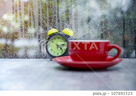 A coffee cup and alarm clock on the table 107891523