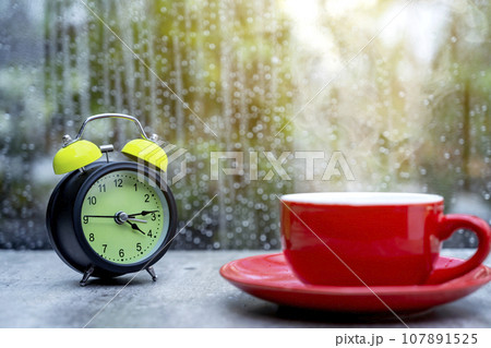 A coffee cup and alarm clock on the table 107891525