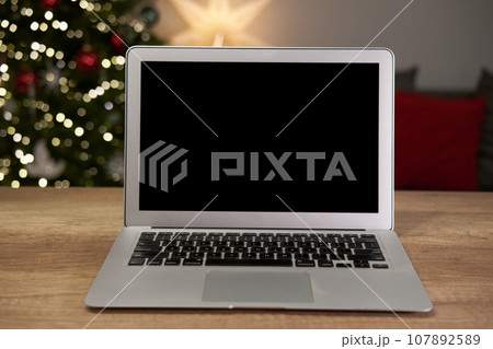 Laptop computer with blank screen in living room with Christmas decor. Mock up copy space. 107892589