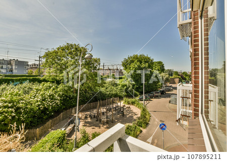 an outside area with trees, bushes, and buildings in the distance is taken from a window on a sunny day 107895211