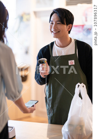 二次元バーコードを読み取る男性店員 107896317