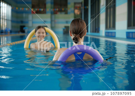 Female fitness class of aqua aerobics at indoors swimming pool Female fitness class of aqua aerobics at indoors swimming pool 107897095