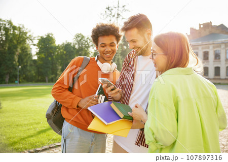 Group of teenager students laughing while watching funny video on mobile phone 107897316