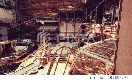 A dilapidated building with rusted metal debris scattered on the ground A dilapidated building with rusted metal debris scattered on the ground 107898278