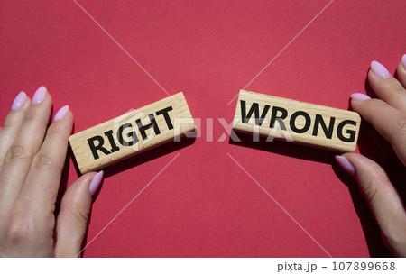 Right or Wrong symbol. Concept word Right or Wrong on wooden blocks. Businessman hand. Beautiful red background. Business and Right or Wrong concept. Copy space 107899668