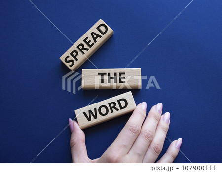 Spread the Word symbol. Concept wordsSpread the Word on wooden blocks. Beautiful deep blue background. Businessman hand. Business and Spread the Word concept. Copy space. 107900111