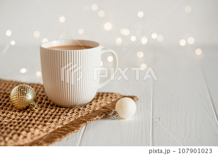 A white cup with hot coffee or tea on a white wooden table. 107901023