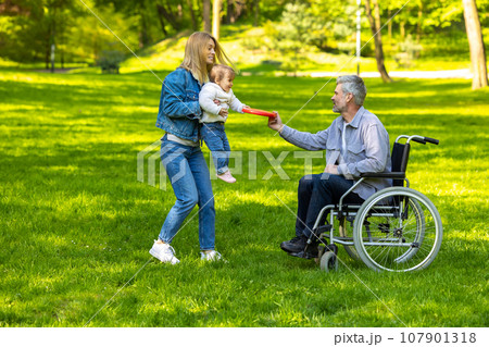 Cute family playing frisbee in the park Cute family playing frisbee in the park 107901318