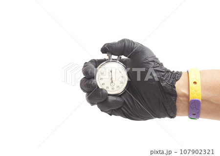 doctor's hand in black surgical medical gloves holds an activated mechanical stopwatch. 107902321