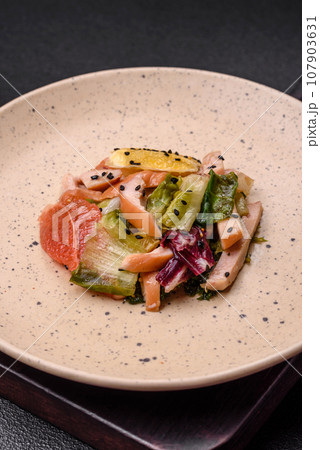 Delicious fresh juicy salad of sliced chicken, grapefruit, lettuce, sesame with olive oil 107903631