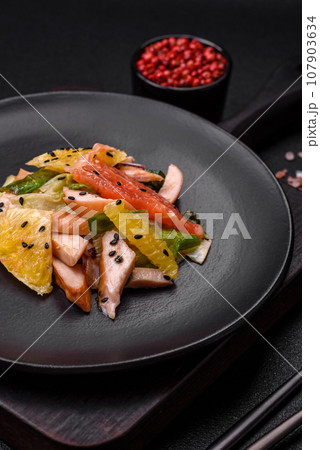 Delicious fresh juicy salad of sliced chicken, grapefruit, lettuce, sesame with olive oil 107903634