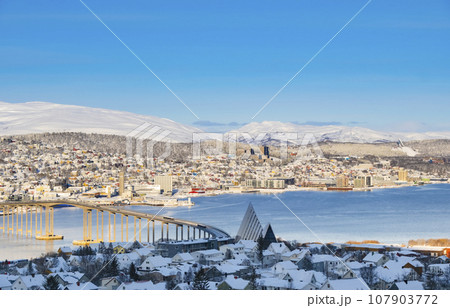 Snowy roofs, embankment near the port and fishing ships, Sunny winter day. 107903772