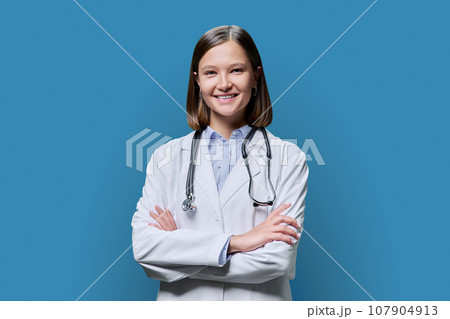 Portrait of young woman doctor student intern in white coat on blue background 107904913