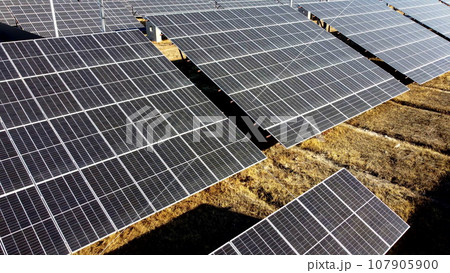 Solar power plant. Flight over modules of solar power station on sunny day. Renewable electrical energy. Photovoltaic modules photobatteries. New modern technology. Alternative green electricity power Solar power plant. Flight over modules of solar power station on sunny day. Renewable electrical energy. Photovoltaic modules photobatteries. New modern technology. Alternative green electricity power 107905900