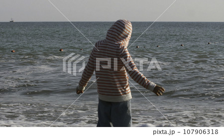 Rear view of a boy along the beach during daytime in Thailand. Creative. Boy child by the sea on a windy day. Rear view of a boy along the beach during daytime in Thailand. Creative. Boy child by the sea on a windy day. 107906318