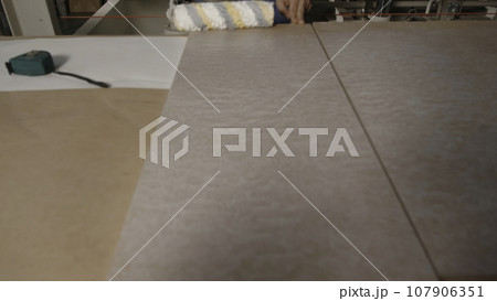 Close up of process of priming wooden board surface at the factory. Industrial background, concept of carpentry. 107906351
