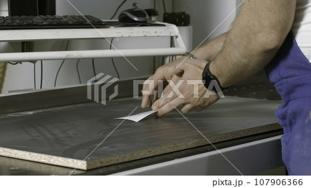 Carpenter putting paper sticker on a wooden board. Creative. A man works with a tree, woodworking and traditional carpentry. 107906366