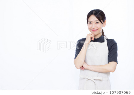 白い背景の前で笑顔で考えている30代の主婦 107907069