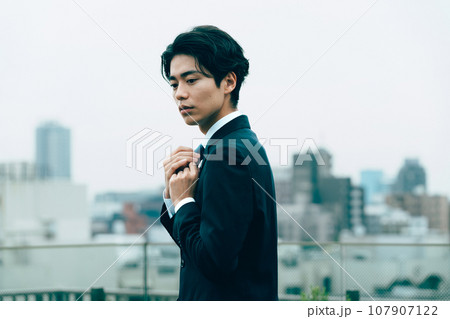 都会でネクタイを整える若いビジネスマン 107907122