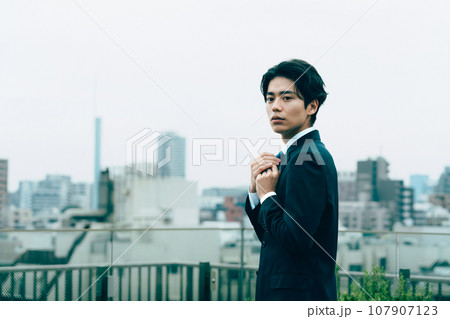 都会でネクタイを整える若いビジネスマン 107907123