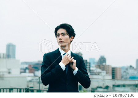 都会でネクタイを整える若いビジネスマン 107907130