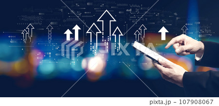 Rising arrow theme with businessman using a tablet computer Rising arrow theme with businessman using a tablet computer 107908067