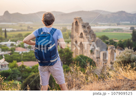 Man tourist explores Aspendos Ancient City. Aspendos acropolis city ruins, cisterns, aqueducts and old temple. Aspendos Antalya Turkey. turkiye Man tourist explores Aspendos Ancient City. Aspendos acropolis city ruins, cisterns, aqueducts and old temple. Aspendos Antalya Turkey. turkiye 107909525