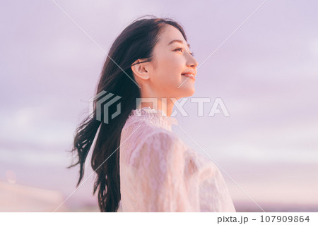 夕日バックの女性ポートレート 107909864