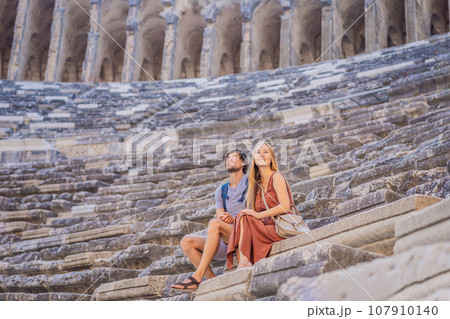 Happy couple man and woman tourists explores Aspendos Ancient City. Aspendos acropolis city ruins, cisterns, aqueducts and old temple. Aspendos Antalya Turkey. turkiye Happy couple man and woman tourists explores Aspendos Ancient City. Aspendos acropolis city ruins, cisterns, aqueducts and old temple. Aspendos Antalya Turkey. turkiye 107910140