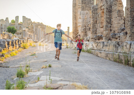 dad and son tourists at the ruins of ancient city of Perge near Antalya Turkey. Traveling with kids concept dad and son tourists at the ruins of ancient city of Perge near Antalya Turkey. Traveling with kids concept 107910898