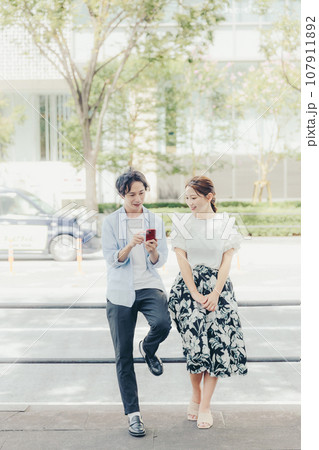路上でスマホを見る男女 107911892