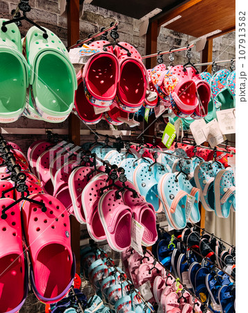 Multicolored children rubber flip flops hanging on racks in a supermarket Multicolored children rubber flip flops hanging on racks in a supermarket 107913582