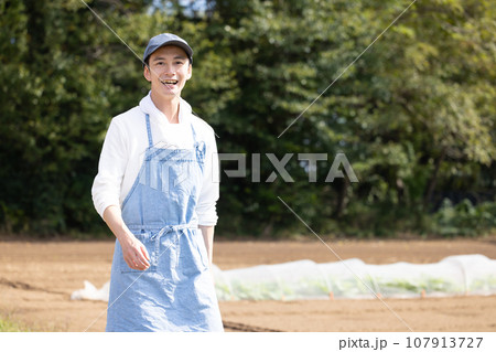 畑を歩く若い男性 107913727