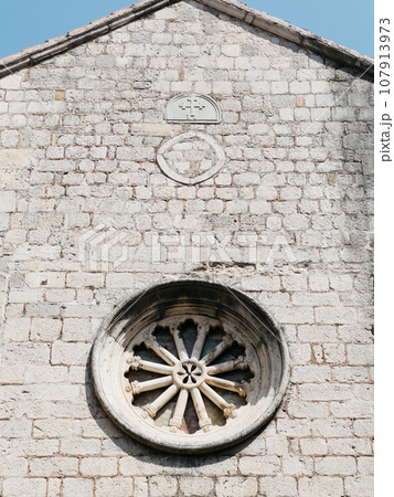 Rose window on the stone wall of an old church Rose window on the stone wall of an old church 107913973