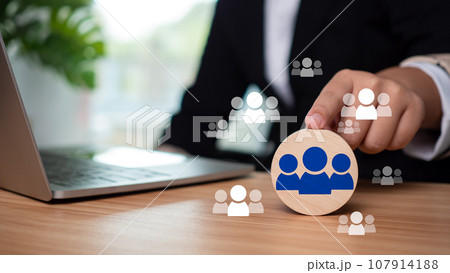 Businessman points finger at circular wooden plank to select business target audience and target customers 107914188