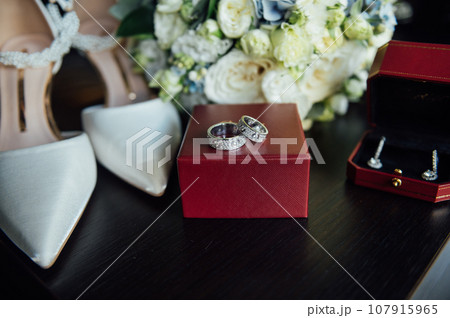 Wedding set of the bride. Shoes and rings lie next to the wedding bouquet 107915965