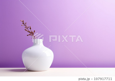White round vase with a flower on a purple wall background White round vase with a flower on a purple wall background 107917711