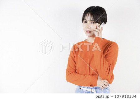 電話をしながらこちらを見る20代女性 電話をしながらこちらを見る20代女性 107918334