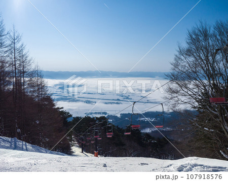 スキー場の高みから雲海に覆われた湖と雪の町を望む (福島県、猪苗代) 107918576