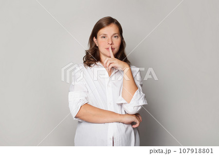 Girl or boy? Pregnant woman holding her finger near her lips and showing shhh gesture.  107918801