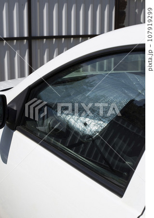 A sun reflector inside a white car parked in the yard. Solar reflector protects the plastic of the car from heating. 107919299