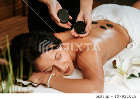 Beautiful young woman in the massage salon with brown curly hair and healthy skin. Masseur and patient concept. Beautiful young woman in the massage salon with brown curly hair and healthy skin. Masseur and patient concept. 107921018