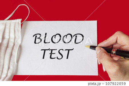 Medical concept. The phrase BLOOD TEST is written by a female hand on a notebook, next to Medical concept. The phrase BLOOD TEST is written by a female hand on a notebook, next to 107922059