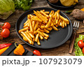 French fries served on black plate and wooden table 107923079